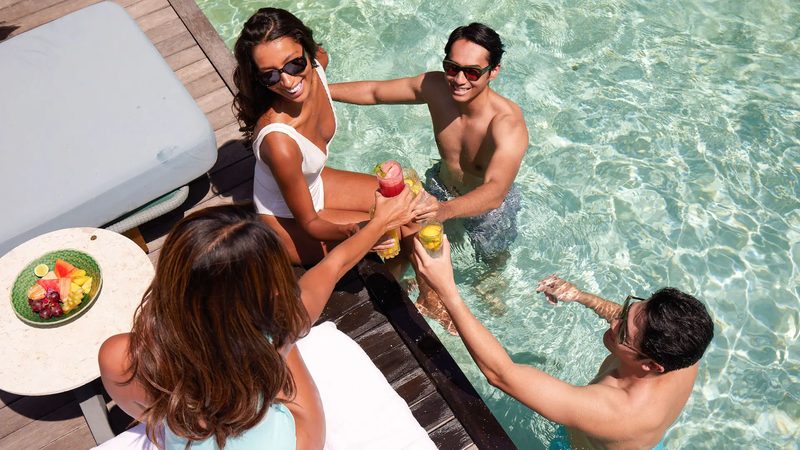 Guests raising a toast at the edge of the pool in the afternoon sun